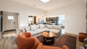 A spacious living area with a sectional sofa, a coffee table, and a view into the kitchen.