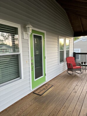 A porch with a green door, a rocking chair, and a doormat. - Winter Rates at Seize the Bay (Port St. Joe)