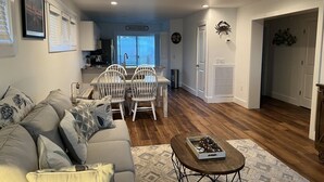 A living room with a sofa, chairs, a coffee table, and a dining area with a table and chairs. - Winter Rates at Seize the Bay (Port St. Joe)
