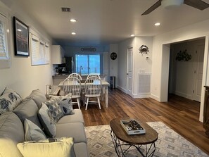 A living room with a sofa, chairs, a coffee table, and a dining area with a table and chairs. - Winter Rates at Seize the Bay (Port St. Joe)
