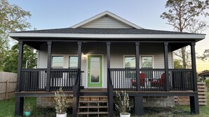 A two-story house with a porch, a green door, and a small garden with potted plants. - Winter Rates at Seize the Bay (Port St. Joe)