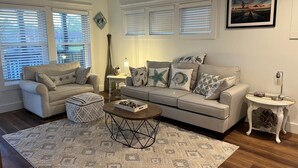 A living room with a sofa, ottoman, coffee table, and a side table with a lamp. - Winter Rates at Seize the Bay (Port St. Joe)