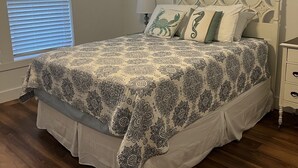 A bedroom with a bed, a ceiling fan, a nightstand, and a window with blinds. - Winter Rates at Seize the Bay (Port St. Joe)
