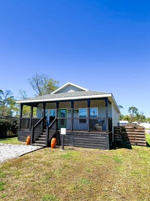 A small, single-story house with a porch, a staircase, and a front door. - Winter Rates at Seize the Bay (Port St. Joe)