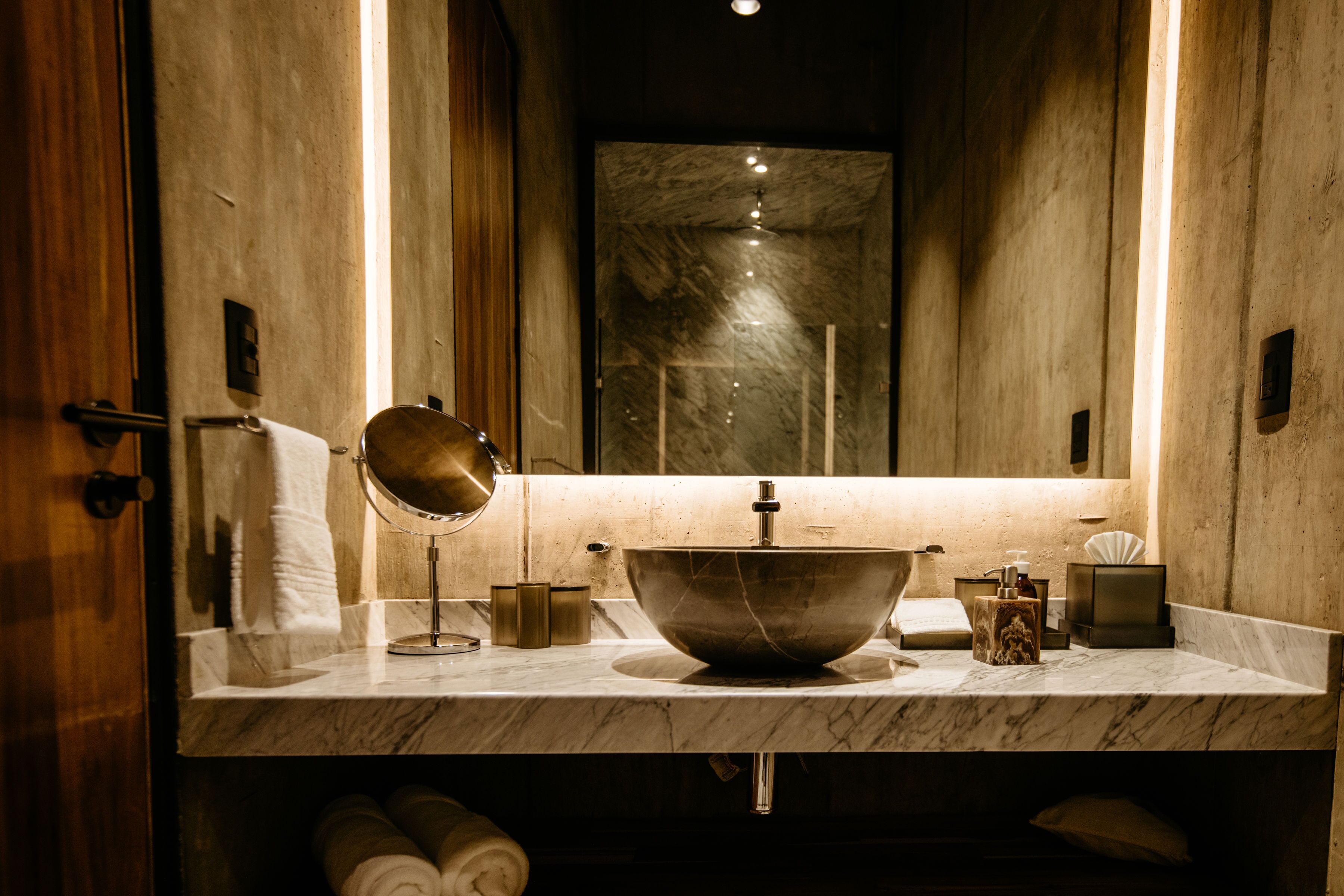 Un bany amb un lavabo de marbre, un mirall i un suport per a tovalloles.