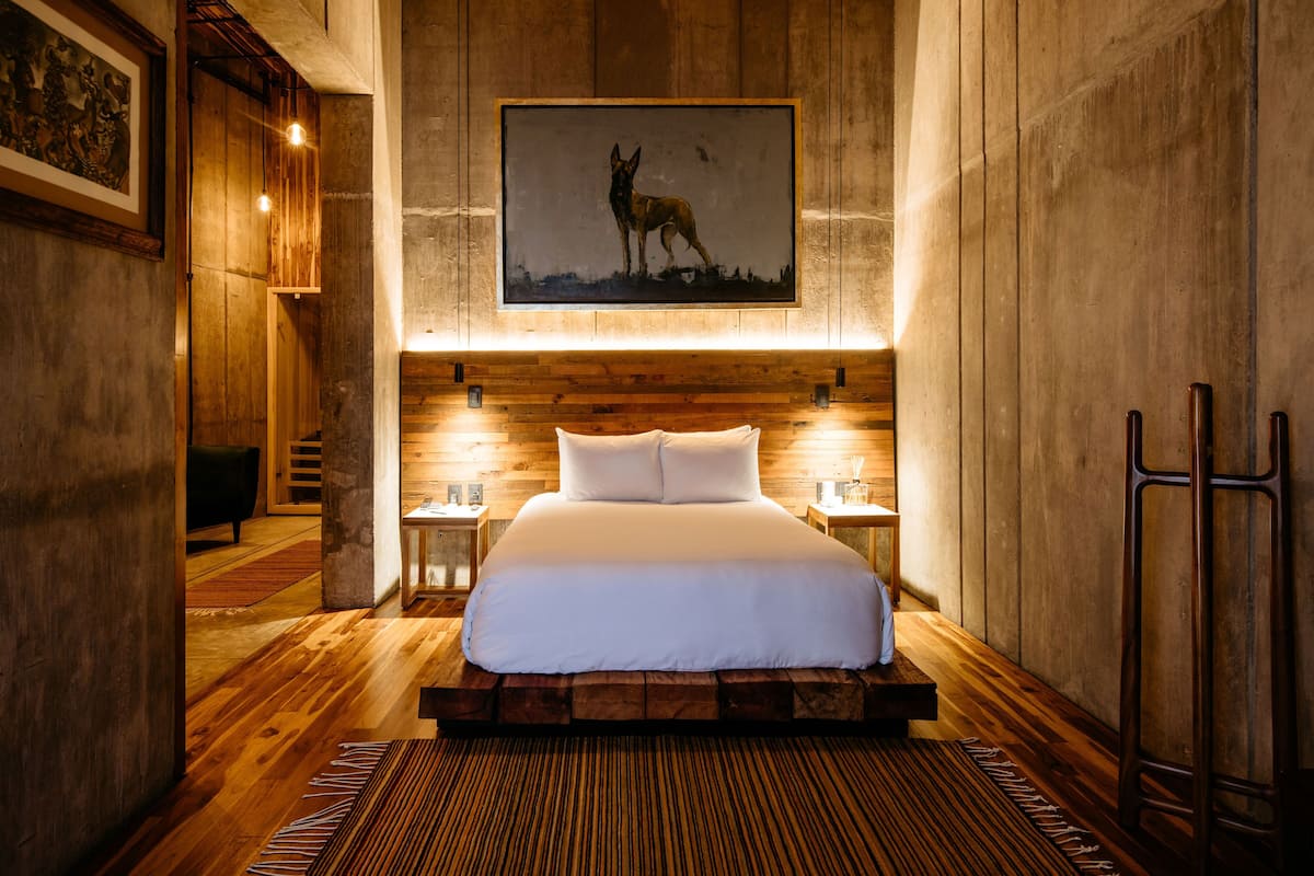 Un dormitorio con una cama grande, paredes de madera y un cuadro enmarcado de un perro.