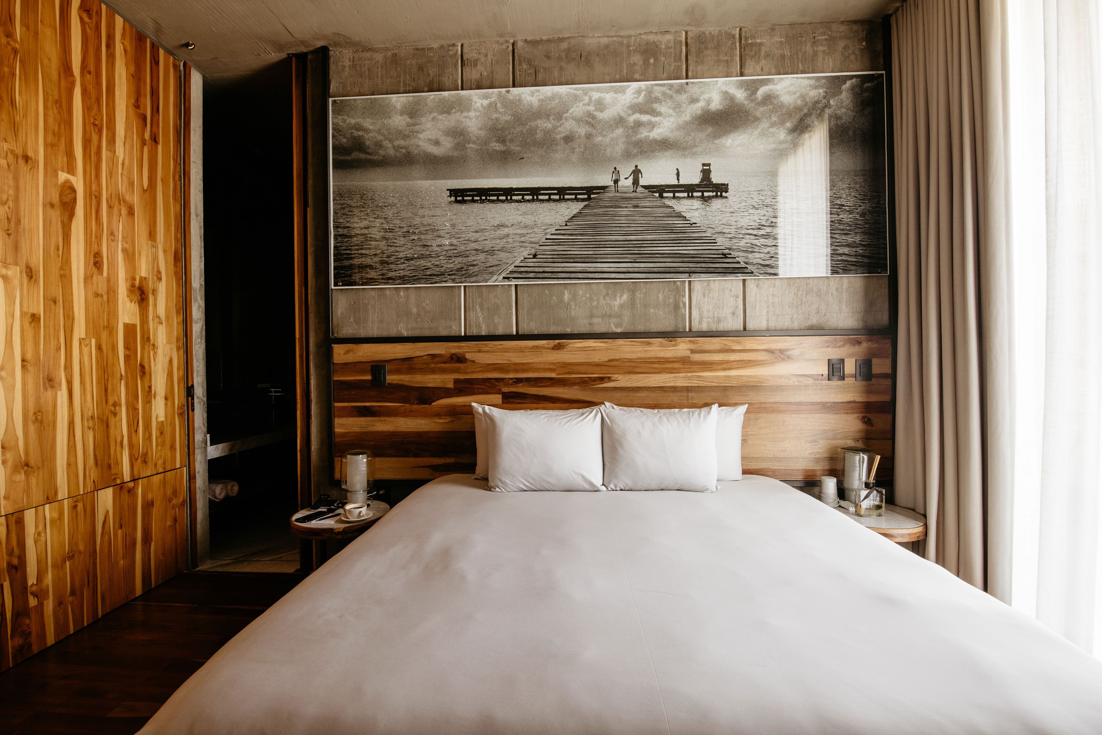 Un dormitorio con una cama grande, cabecera de madera y un cuadro en la pared que muestra un muelle.