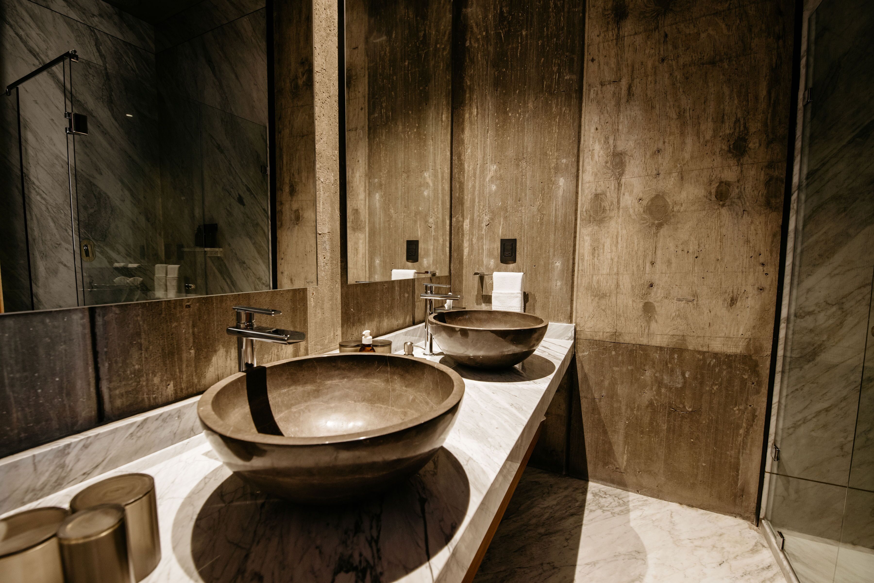 A modern bathroom with a large mirror, two sinks with large bowls, and wooden paneling.