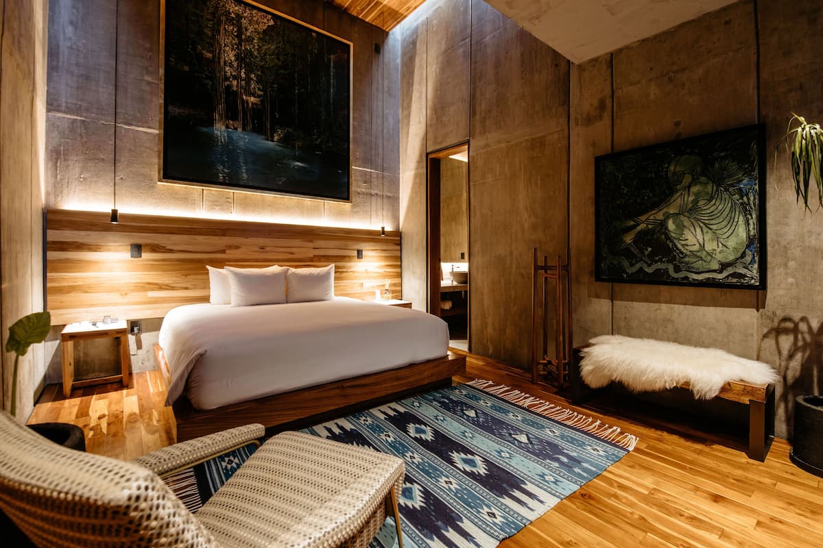 Un dormitorio moderno con una cama grande, suelo de madera y un cuadro de gran tamaño en la pared.