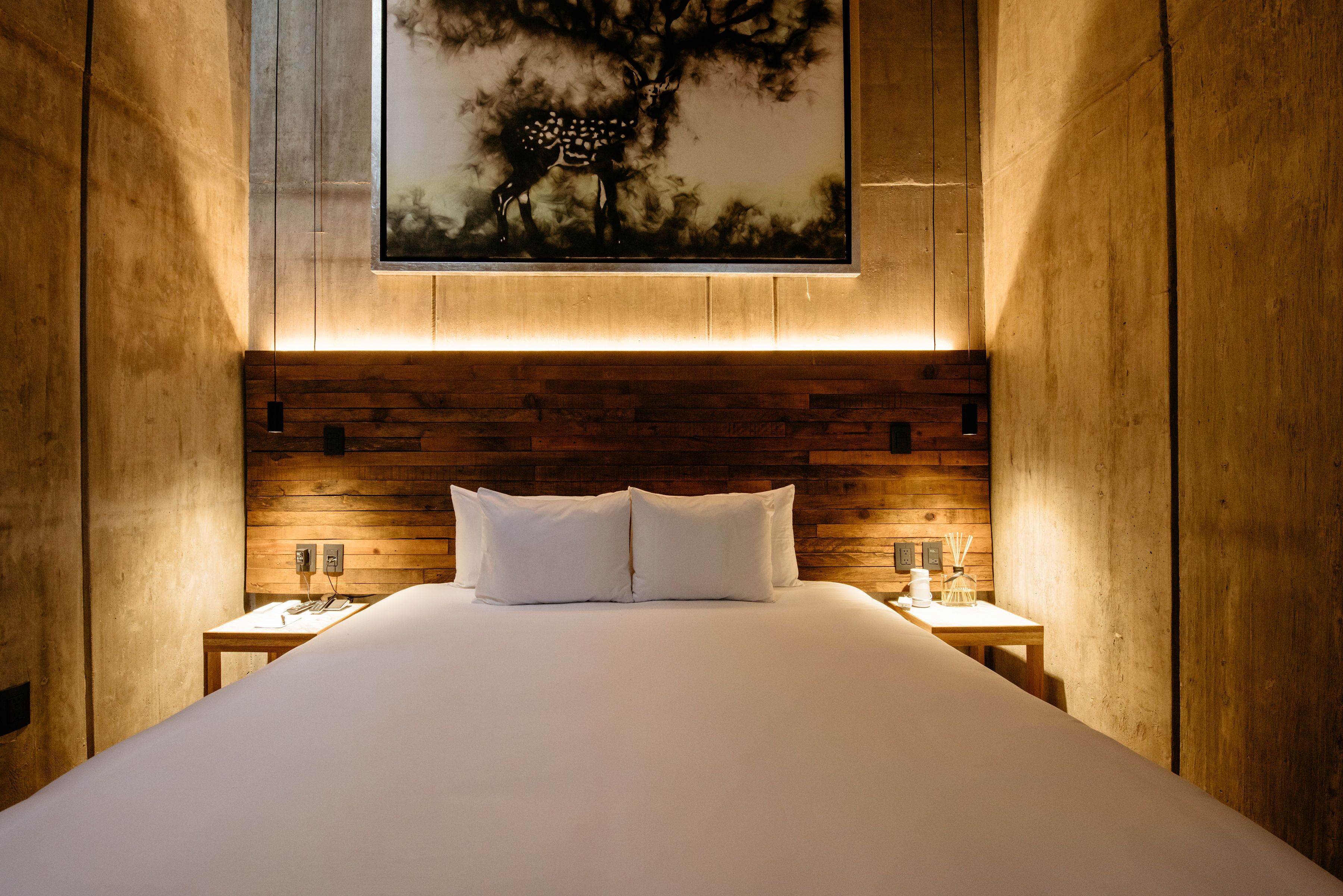 A large bed with white linens, wooden headboard, and two bedside tables with lamps.
