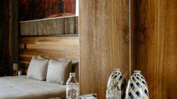 Una habitación de hotel con cabecera de madera, cama con ropa de cama blanca, una mesa de comedor con vajilla y un cuadro en la pared.