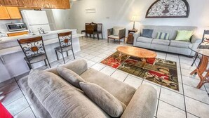 A living room with a sofa, chairs, a coffee table, and a dining area with chairs and a table.
