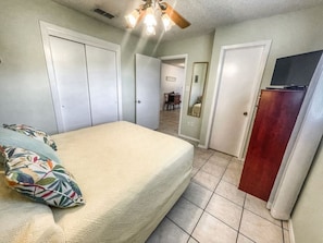 A bedroom with a bed, a ceiling fan, and a dresser.