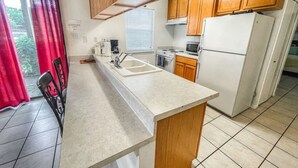 A compact kitchen with wooden cabinets, a white refrigerator, a sink, and a stove.