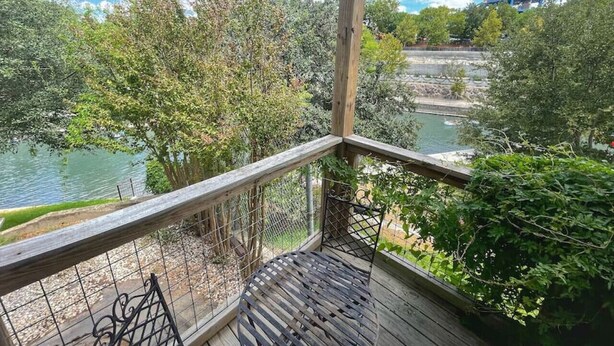 A wooden deck with a metal railing overlooking a river and trees.
