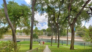 A pathway leading to a park with trees and a body of water.