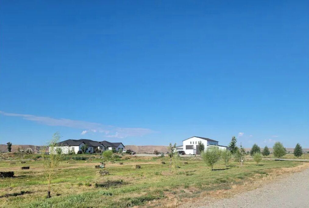 A residential area with houses and open fields under a clear sky.
