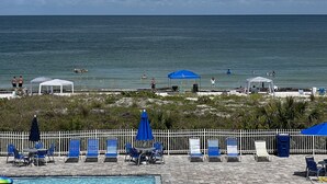 Uitzicht op een strand met een zwembad, ligbedden en parasols.