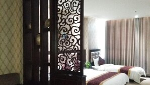 A hotel room with two beds, a large window with curtains, a decorative partition, and a sofa. - Jinshan Hotel (Dunhuang)