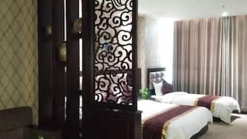 A hotel room with two beds, a decorative screen, a sofa, and a large window with curtains.