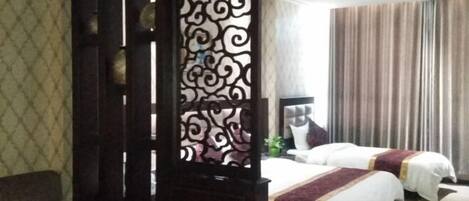 A hotel room with two beds, a decorative screen, a sofa, and a large window with curtains.