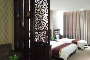 A hotel room with two beds, a decorative screen, a sofa, and a large window with curtains. - Jinshan Hotel (Dunhuang)