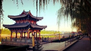 A traditional pavilion with a tiled roof, a paved walkway, and a fence. - Jinshan Hotel (Dunhuang)