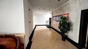 A hallway with a marble floor, a staircase, and a potted plant. - Jinshan Hotel (Dunhuang)