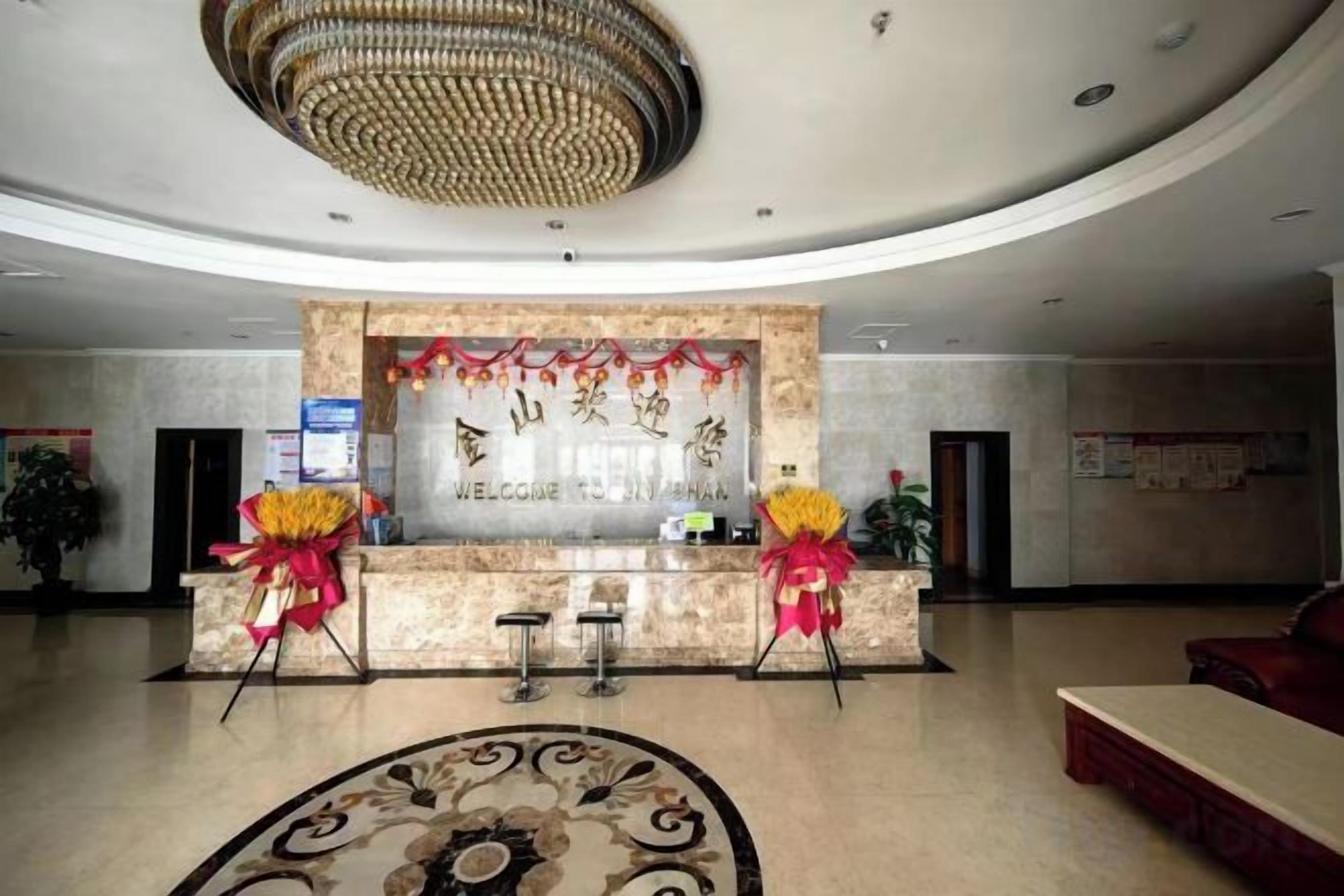 A hotel reception area with a marble counter, two chairs, and a chandelier.
