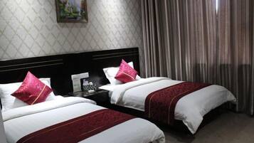 A hotel room with two beds, a nightstand, a painting on the wall, and a window with curtains.