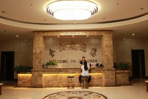 A reception area with a marble wall, a chandelier, and a sign that reads 'WELCOME TO JI SHAN'. - Jinshan Hotel (Dunhuang)