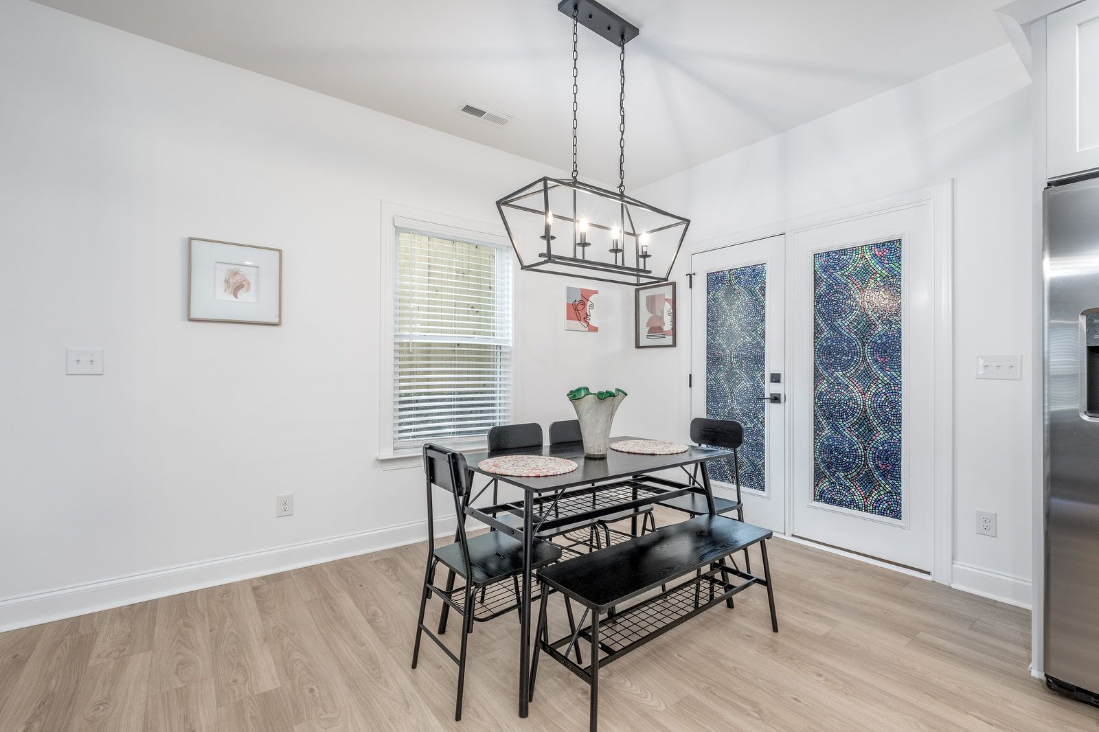A modern kitchen with a dining table, chairs, and a hanging light fixture.