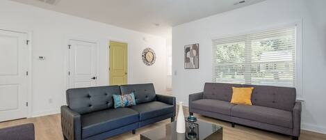 Un salon moderne avec deux canapés, une table basse et un ventilateur de plafond.