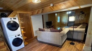 Un espacio habitable compacto con lavadora, sofá y televisor.