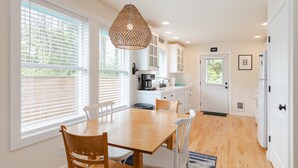Une cuisine moderne avec un coin repas, des meubles blancs et un luminaire suspendu.