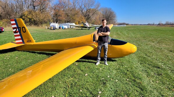 A yellow airplane with a red, white, and blue tail fin, parked on a grassy field. - HARMONY INN (Huntley)