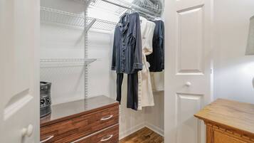 Un armario vestidor con repisas abiertas, ropa colgada y cajones de madera.