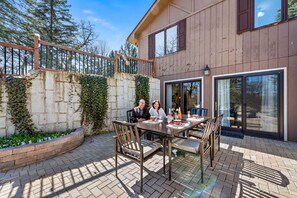 A patio with a table and chairs, a stone wall with greenery, and a wooden fence.