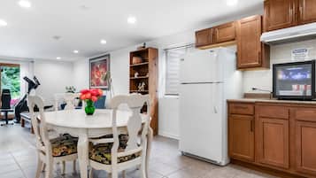 A kitchen with wooden cabinets, a white refrigerator, and a dining table with chairs.