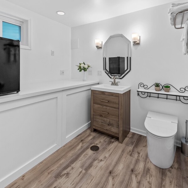 Un baño con tocador blanco, mueble de madera y un inodoro blanco.