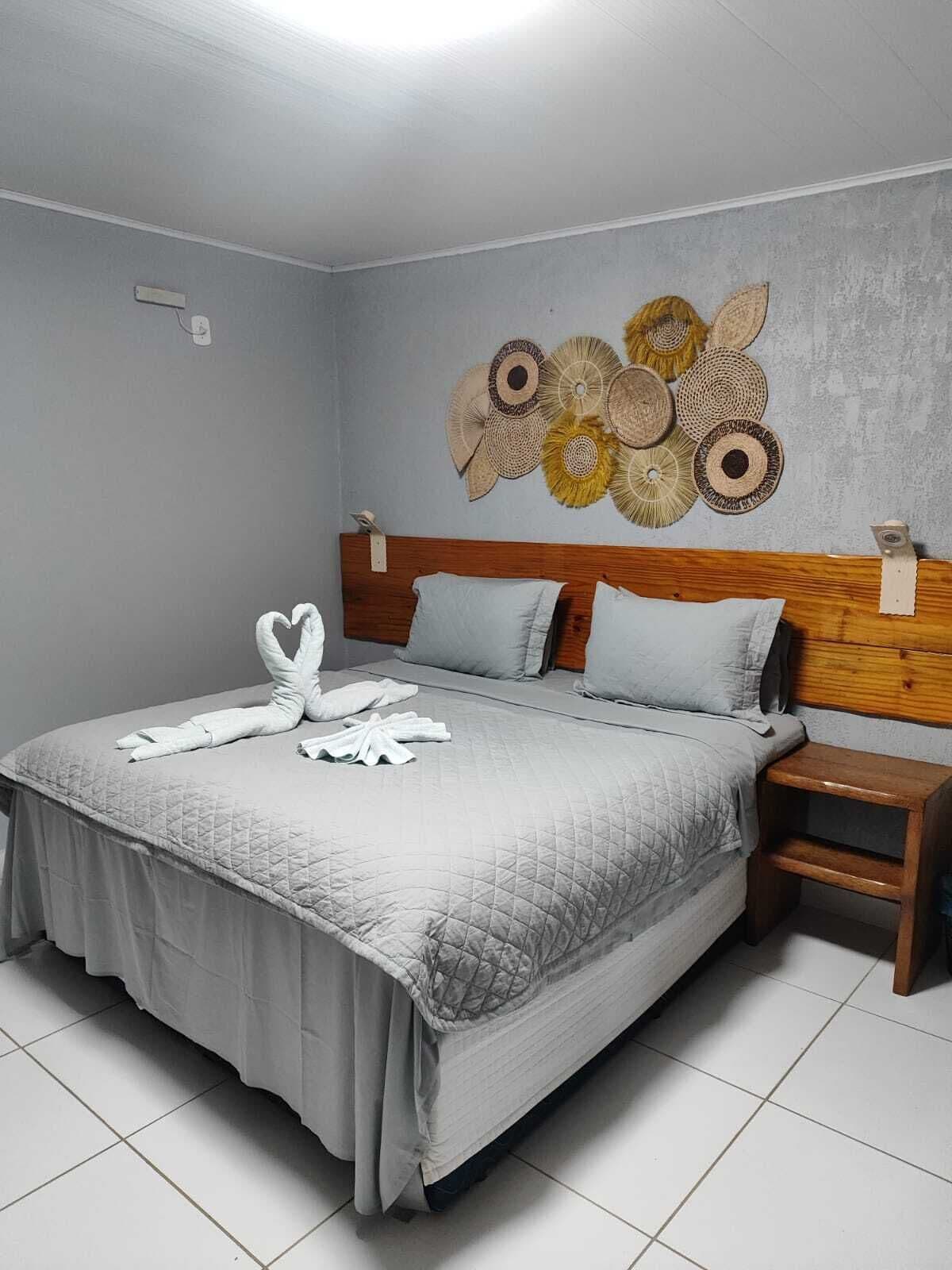 A neatly made bed with a quilted bedspread and pillows, a wooden headboard, and a wall art piece above it.
