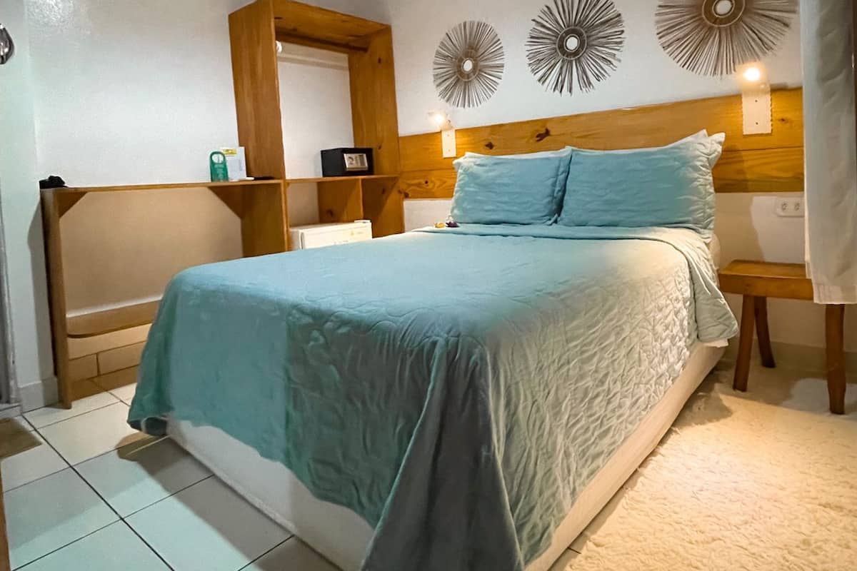 A bedroom with a bed, wooden headboard, bedside tables, a mirror, and wall decor.