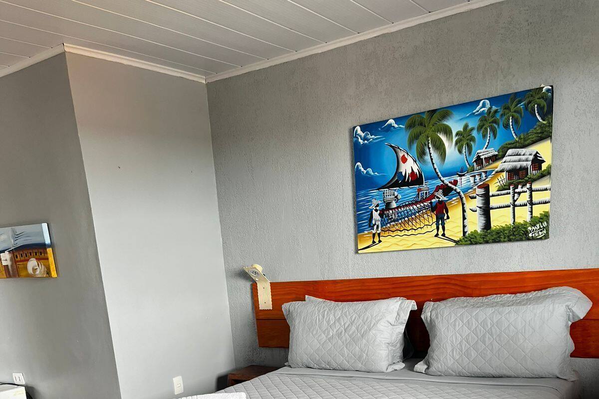 A hotel room with a bed, a painting on the wall, and a nightstand.