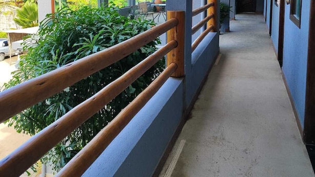 Un pasillo con barandilla de madera, ventanas amplias y una lámpara colgante.