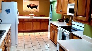 A kitchen with wooden cabinets, a refrigerator, a microwave, and a stove. - The Highland Hideaway, perfect for family getaways (Piercetown)