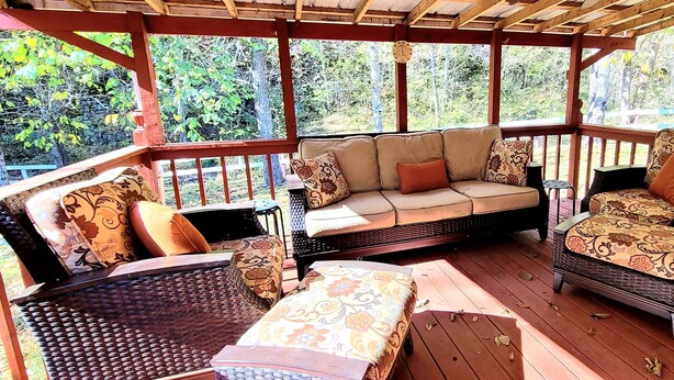 A covered outdoor seating area with wicker furniture and patterned cushions. - The Highland Hideaway, perfect for family getaways (Piercetown)