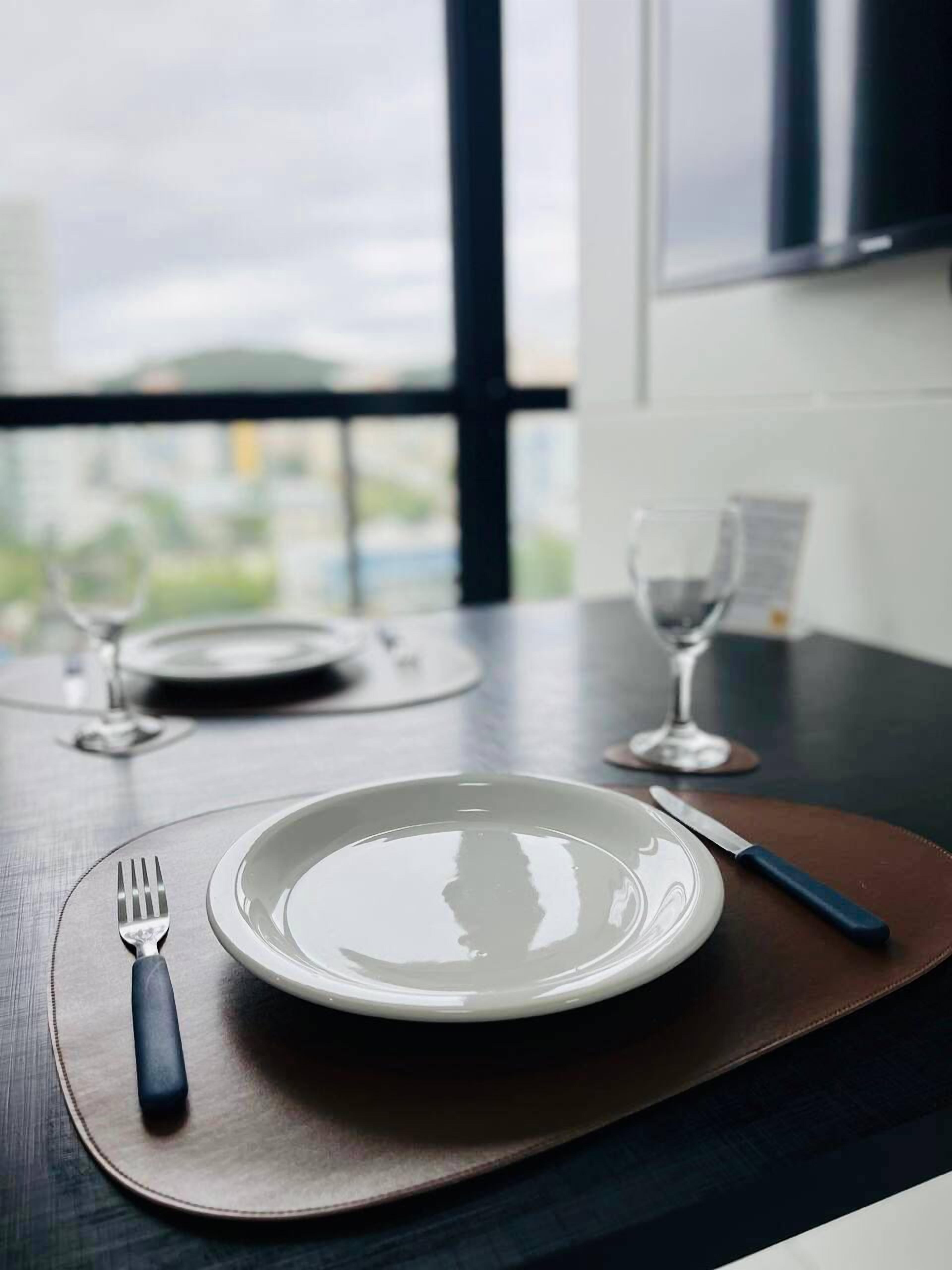 A dining table with a plate, fork, knife, and glass set for a meal.