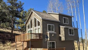 A two-story house with a balcony, a satellite dish, and a view of a forested area. - Mountain Getaway and Family Retreat (Woodland Park)