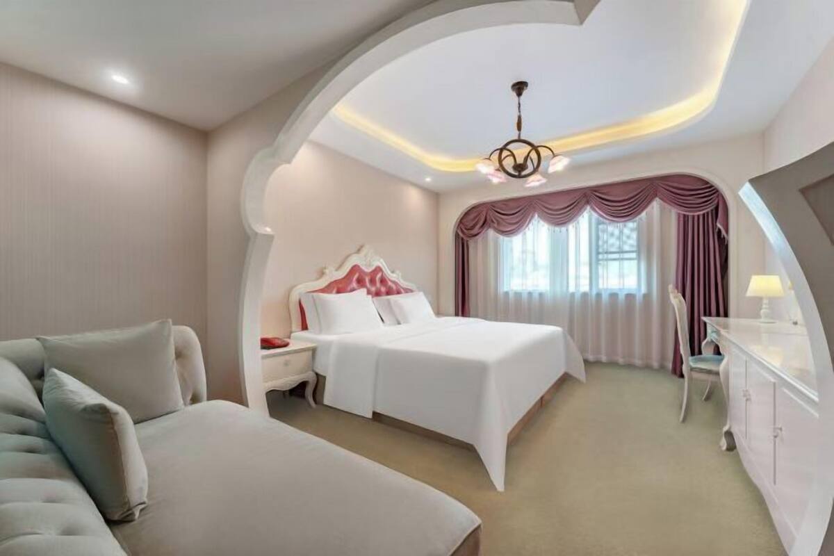 Quarto de hotel com cama, escrivaninha, cadeira e design de teto curvo.