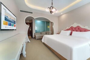 Habitación de hotel con una cama grande, un televisor montado en la pared y un original arco de entrada a otra habitación.